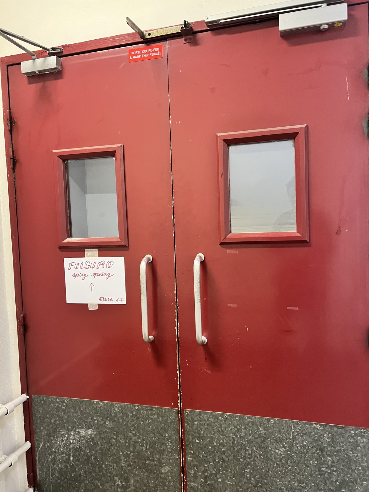 Porte rouge avec le panneau manuscrit Fulguro spring opening, flèche pointant vers le haut, Atelier 1.7